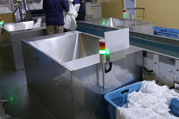 リネン工場に入荷したリネン品を効率よく少人数で仕分け、計量できる入荷仕分けシステム